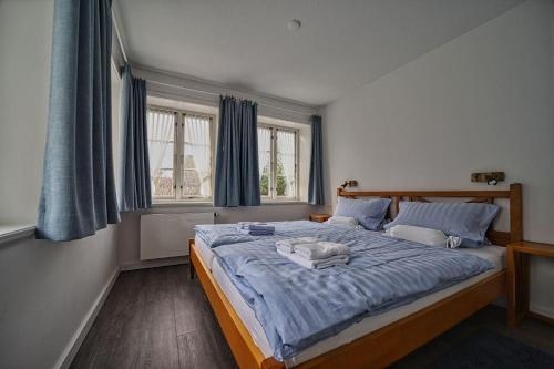 - une chambre dotée d'un grand lit avec des draps bleus et des fenêtres dans l'établissement Wohnung-Suedwind, à Süddorf