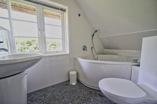 a bathroom with a toilet and a tub and a sink at Haus-unter-Reet in Nebel