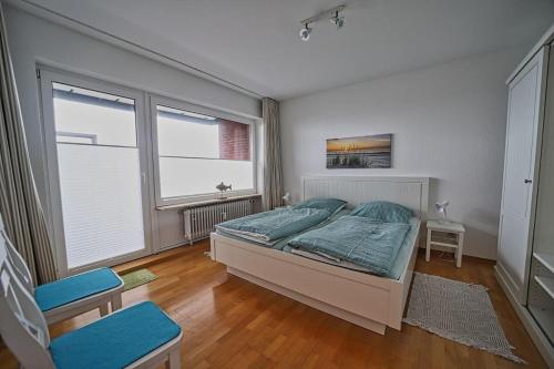 a bedroom with a bed and two windows at Wohnung-Froemming in Wittdün