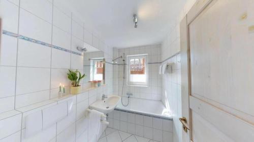 a white bathroom with a sink and a bath tub at Wohnung-1 in Wittdün