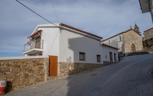 a white building with a window on a street at Casas do relógio in Penamacor