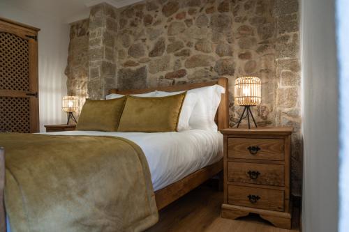 a bedroom with a bed with a stone wall at Casas do relógio in Penamacor
