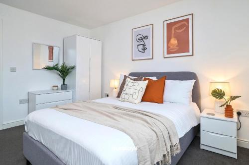 a bedroom with a large white bed with orange pillows at Denton House by Truestays - NEW 3 Bedroom House in Manchester in Manchester
