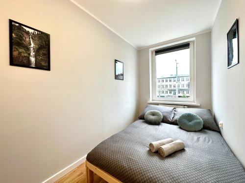 1 dormitorio con cama con almohadas y ventana en MMRent Waterfall Room en Gdansk