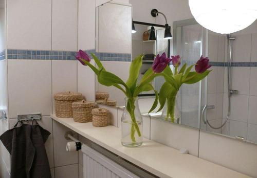a vase with purple flowers on a counter in a bathroom at Wohnung-Kaufhold in Wittdün