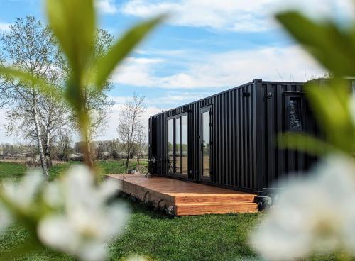 uma pequena casa preta numa plataforma de madeira num campo em Wooden house and modern container in Lekneno, near Zagreb em Lekneno