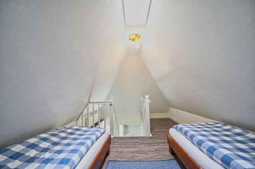a attic room with two beds and a staircase at Wohnung-Landwind in Süddorf