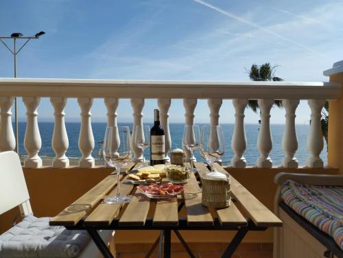 ein Tisch mit Weingläsern und Essen auf einem Balkon in der Unterkunft Apartamentos Playacala in La Cala del Moral