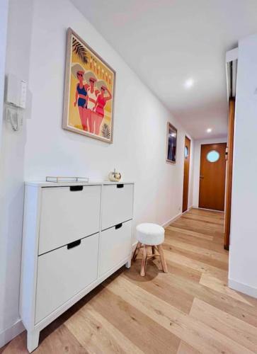 Cette chambre blanche dispose d'une commode et d'un tabouret. dans l'établissement Le Greco : Apt 6 Prs, 3 Ch, Parking, Clim, à Antibes