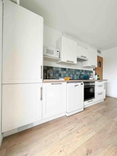 Il comprend une cuisine blanche avec des placards blancs et du parquet. dans l'établissement Le Greco : Apt 6 Prs, 3 Ch, Parking, Clim, à Antibes