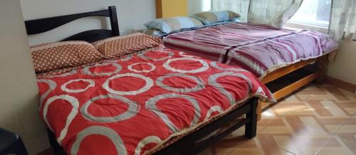 2 camas en una habitación con manta roja y blanca en Hostal Panoramic, en Churín