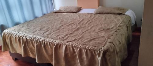 1 cama con colcha marrón y almohadas en Hostal Panoramic, en Churín