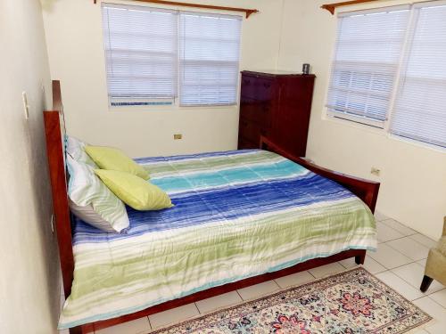 a small bedroom with a bed with yellow pillows at Beautiful 2-Bedroom Near Airport - Powell's Main Road, Antigua in Carlisle