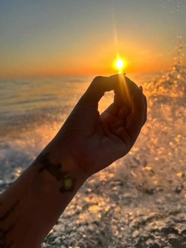 a person holding the sun in front of the ocean at Casa Bella in Jacó