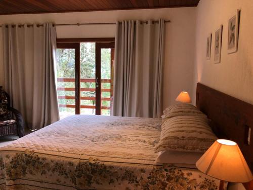 una camera con un grande letto e una finestra di Villa Uliana - Bangalôs VILLA a Domingos Martins