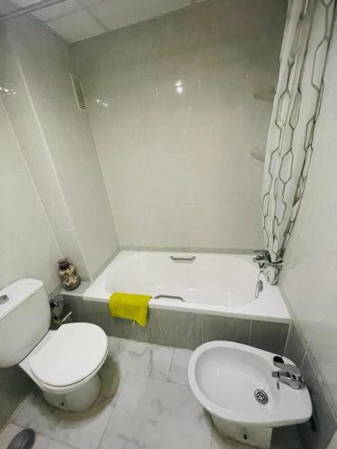 a bathroom with a toilet and a tub and a sink at Bonito apartamento de la playa in Villajoyosa