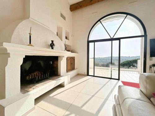 ein Wohnzimmer mit einem Kamin und einem großen Fenster in der Unterkunft Villa Les Pariades : 8 Prs, 4 ch, Piscine, Vue mer in Vallauris
