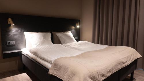 Hotel Nørreport في هولستيبرو: غرفة نوم بسرير كبير عليها شراشف ووسائد بيضاء