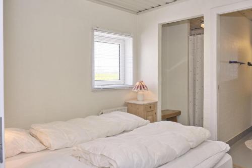 a bedroom with a bed with white sheets and a window at Beautiful Home In Ebeltoft With 3 Bedrooms in Ebeltoft
