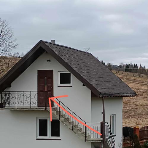 a white house with a black roof and a balcony at DOLINA ROZTOKI-mieszkanie,pokoje lub domek z lokalem na poddaszu in Bircza