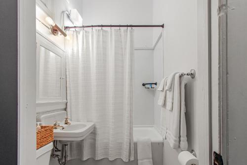 a white bathroom with a shower curtain and a sink at Library Square Suites in Toledo