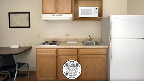 a kitchen with a white refrigerator and a table at WoodSpring Suites Amarillo East I-40 in Amarillo