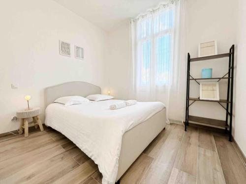 ein weißes Schlafzimmer mit einem großen Bett und einem Fenster in der Unterkunft Le Bruna: Apt 4 prs, Clim, 10 min plages in Antibes