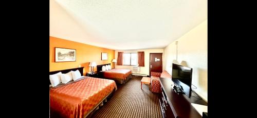 a hotel room with two beds and a flat screen tv at Scottish Inn & Suites - Eau Claire in Eau Claire