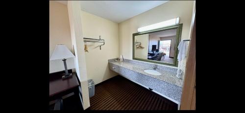 baño con lavabo y espejo grande en Scottish Inn & Suites - Eau Claire, en Eau Claire