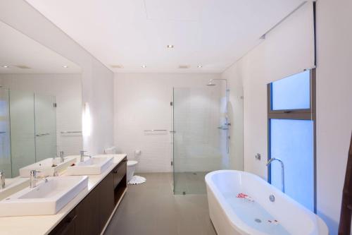 バーン・パクロクにあるBaan Yamu Private Villaの白いバスルーム(シンク2台、シャワー付)