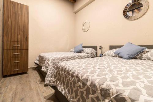 a bedroom with two beds and a clock on the wall at 105 Centrico Zocalo apt 2Bdrm 2bath AC Rooftop in Mexico City