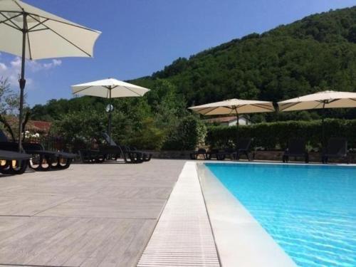 a swimming pool with umbrellas and chairs and a swimming pool at Ferienhaus in Gallicano mit Garten, Grill und gemeinschaftlichem Pool in Gallicano