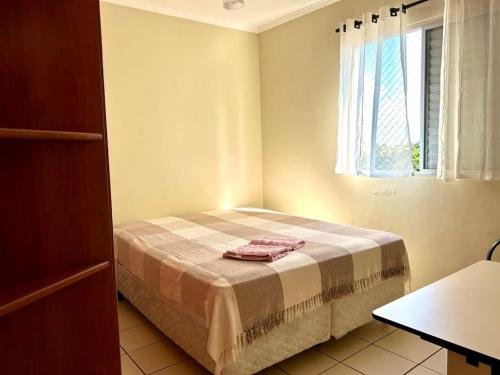 um quarto com uma cama com uma mesa e uma janela em Apartamento Mobiliado em Piracicaba Centro em Piracicaba