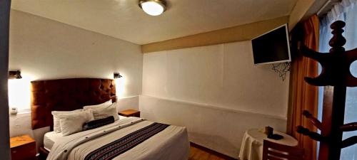 a hotel room with a bed and a television at Hotel Humantay Lodge Ollantaytambo in Ollantaytambo