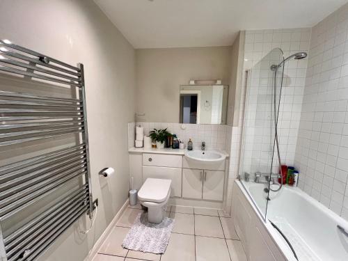 a bathroom with a toilet and a tub and a sink at Entire Apartment next to Canary Wharf in London in London