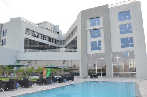 a building with a pool and chairs and umbrellas at Maha Bodhi Hotel.Resort.Convention Centre in Bodh Gaya