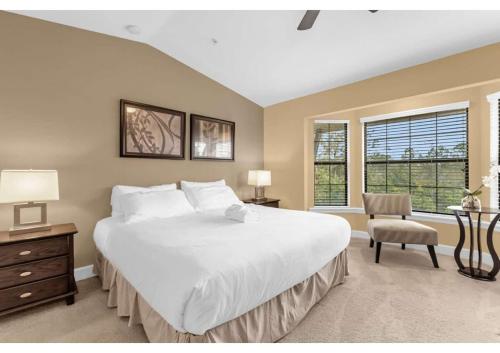 um quarto com uma grande cama branca e uma cadeira em Luxurious Townhome - 5 minutes from Disney em Orlando