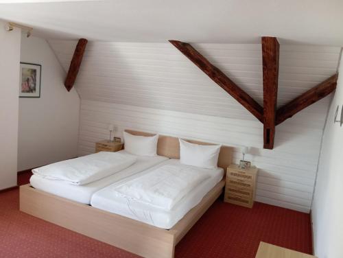 a bedroom with a bed with white sheets and pillows at Hotel Anker in Rottenburg