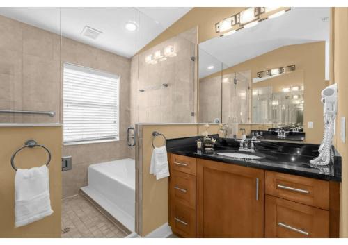 uma casa de banho com um lavatório, uma banheira e um espelho. em Luxurious Townhome - 5 minutes from Disney em Orlando