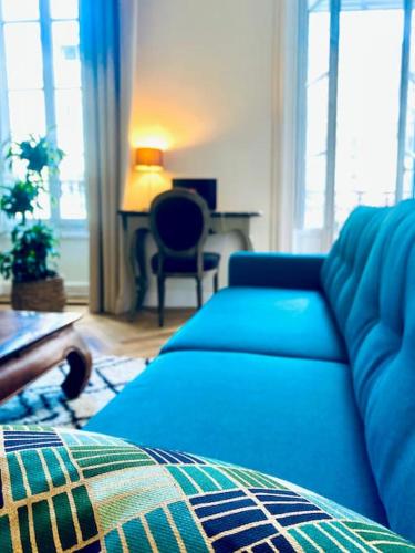 - un salon avec un canapé bleu et un bureau dans l'établissement Le Questel au cœur de la cité romaine avec clim, à Nîmes