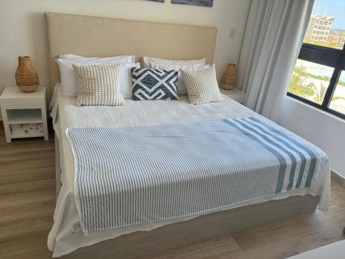 um quarto com uma cama com almofadas e uma janela em Hermoso Apart @the Beach Punta Cana em Punta Cana