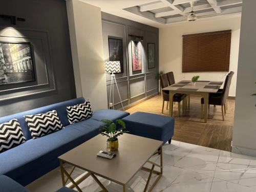 een woonkamer met een blauwe bank en een tafel bij Freddy's Deluxe Family Apartments in Islamabad