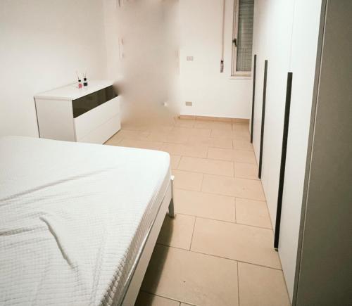 a bedroom with a white bed and a tiled floor at delizioso appartamento a due passi dal mare in Catanzaro Lido