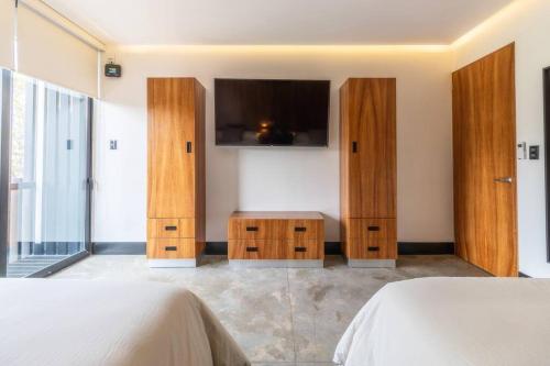 a bedroom with wooden furniture and a tv on the wall at Zielo 1Bdrm 1bath fits 6 AC Rooftop views in Mexico City