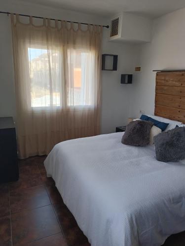 a bedroom with a large white bed with a window at La Casa de Maia in Freila