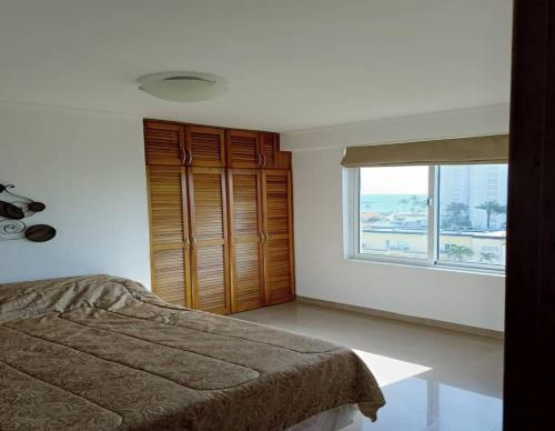 a bedroom with a bed and a large window at Apartamento en La mejor zona de Pampatar. in Pampatar