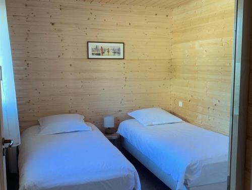 two beds in a room with wooden walls at Gîte Mas des ricochets in Aigremont