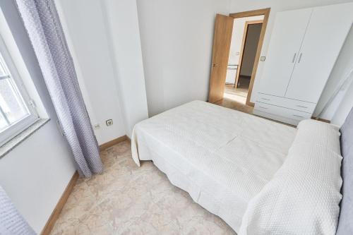 a small bedroom with a bed and a window at Apartamentos Camelle in Camelle