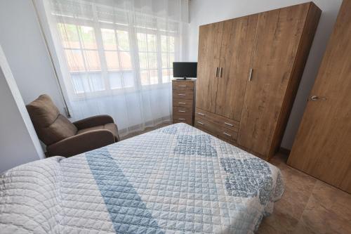 a bedroom with a bed and a dresser and a window at Apartamentos Camelle in Camelle