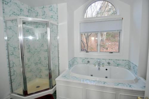 a white bathroom with a tub and a shower at Panorama Peak View- Wifi, Screen Porch, Million Dollar View, Fireplace, Full Kitchen in Berkeley Springs